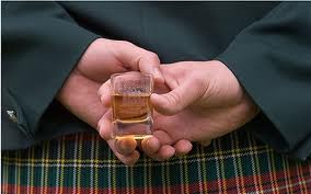 Man in kilt holding a glass of Scotch